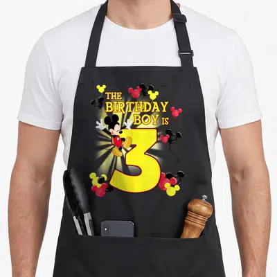 3rd best friend aprons - Mickey Mouse leaning on yellow number 3 with stacked text and Mickey balloons in red black — shown on a black cotton canvas apron against a white background