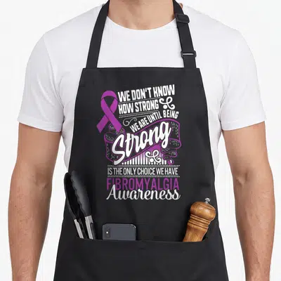 Strong choice aprons - Purple awareness ribbon next to stacked white and purple typography reading We Don't Know How — shown on a black cotton canvas apron against a white background