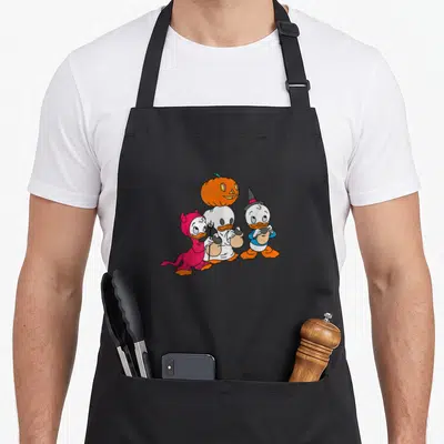 Ducktale halloween apron - Three ducks in devil ghost and wizard costumes with pumpkin on middle head — shown on a black cotton canvas apron against a white background