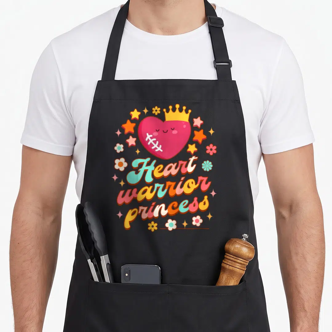 Chd princess apron - Pink heart with crown and stitches surrounded by stars and flowers with Heart warrior princess text — shown on a black cotton canvas apron against a white background