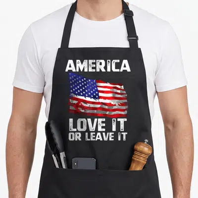 Leave patriotic aprons - Distressed USA flag between AMERICA and LOVE IT OR LEAVE IT text — shown on a black cotton canvas apron against a white background