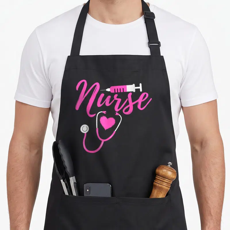 Week nurses apron - Pink Nurse script with syringe and stethoscope forming a heart shape on grey background — shown on a black cotton canvas apron against a white background