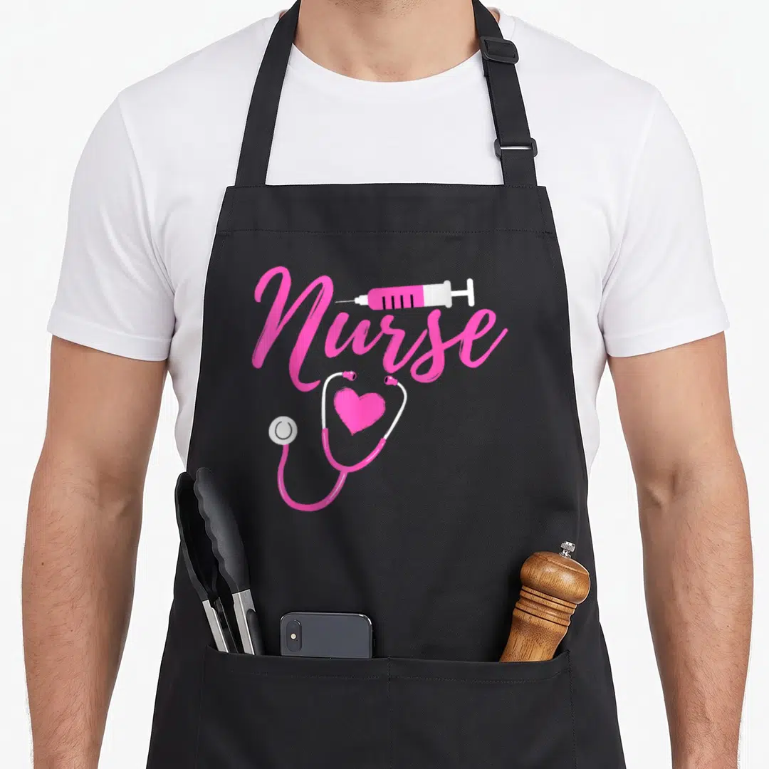 Week nurses apron - Pink Nurse script with syringe and stethoscope forming a heart shape on grey background — shown on a black cotton canvas apron against a white background