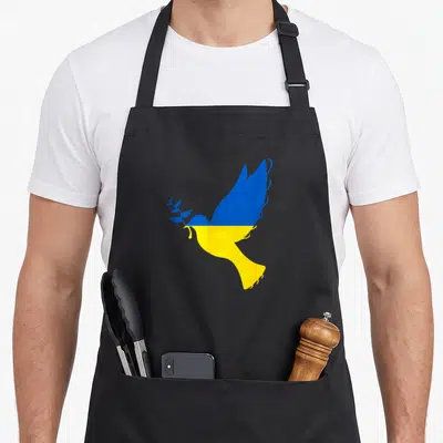 Peace dove dad apron - Minimalist blue and yellow dove in profile holding an olive branch — shown on a black cotton canvas apron against a white background
