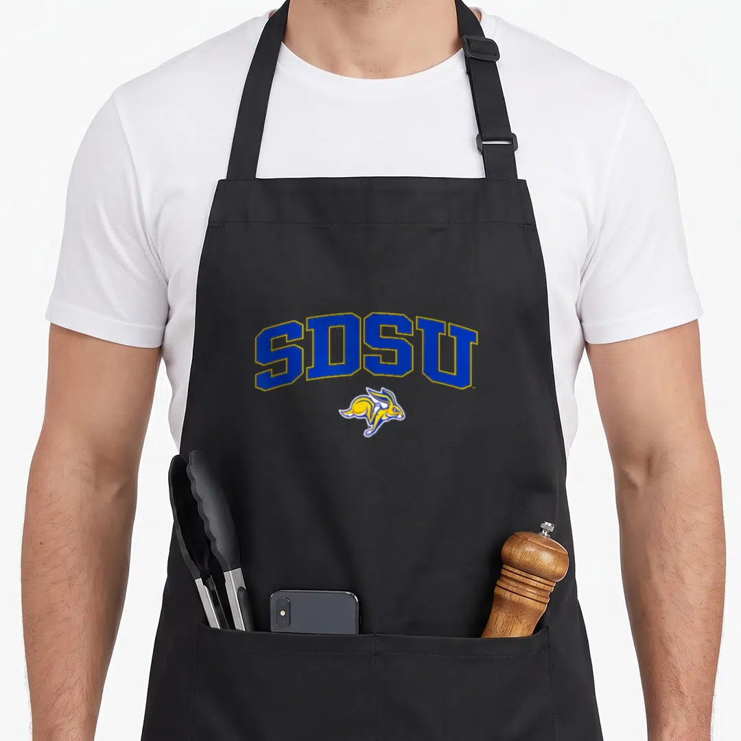 South arch over apron - Arched SDSU text in blue and yellow above a leaping cartoon rabbit mascot — shown on a black cotton canvas apron against a white background
