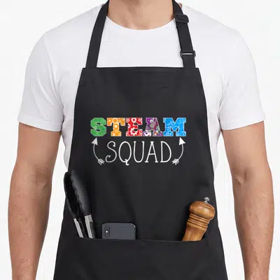 Engineering science apron - Colorful STEAM letters filled with icons above white SQUAD script flanked by two upward — shown on a black cotton canvas apron against a white background