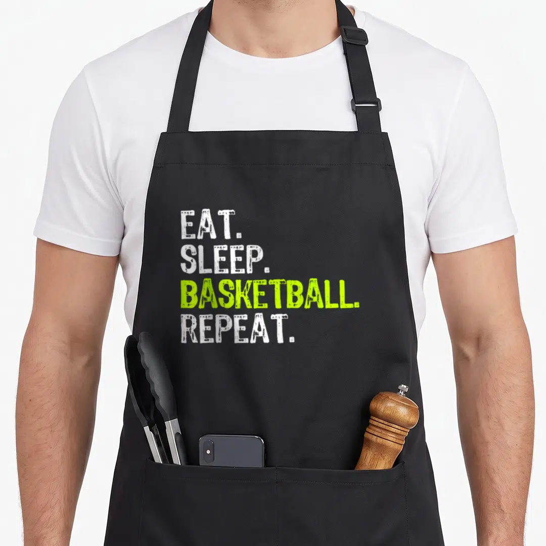 Eat sports fan apron - Stacked white and lime green text reading EAT. SLEEP. BASKETBALL. REPEAT — shown on a black cotton canvas apron against a white background