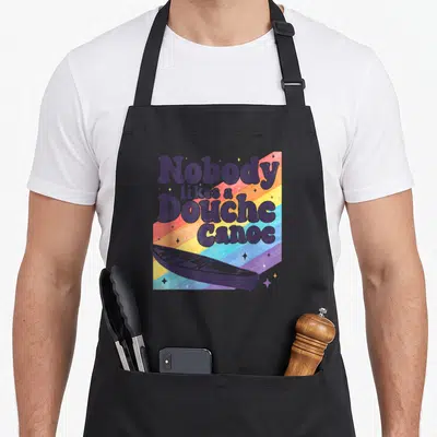 Funny douche canoe apron - Retro rainbow stripes with purple text Nobody likes a Douche Canoe and purple canoe — shown on a black cotton canvas apron against a white background