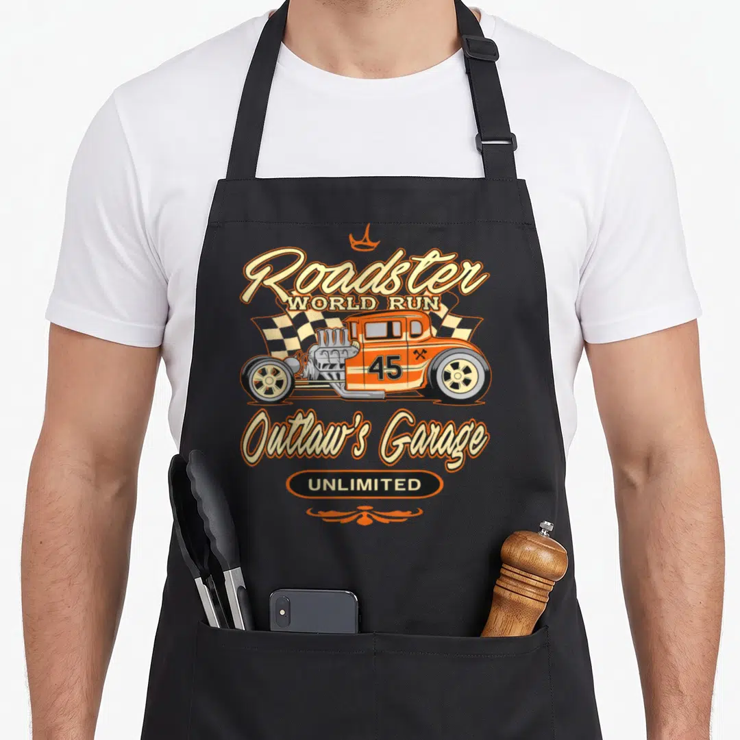 Hot innovation apron - Retro orange hot rod with checkered flag and Roadster World Run Outlaw's Garage text — shown on a black cotton canvas apron against a white background