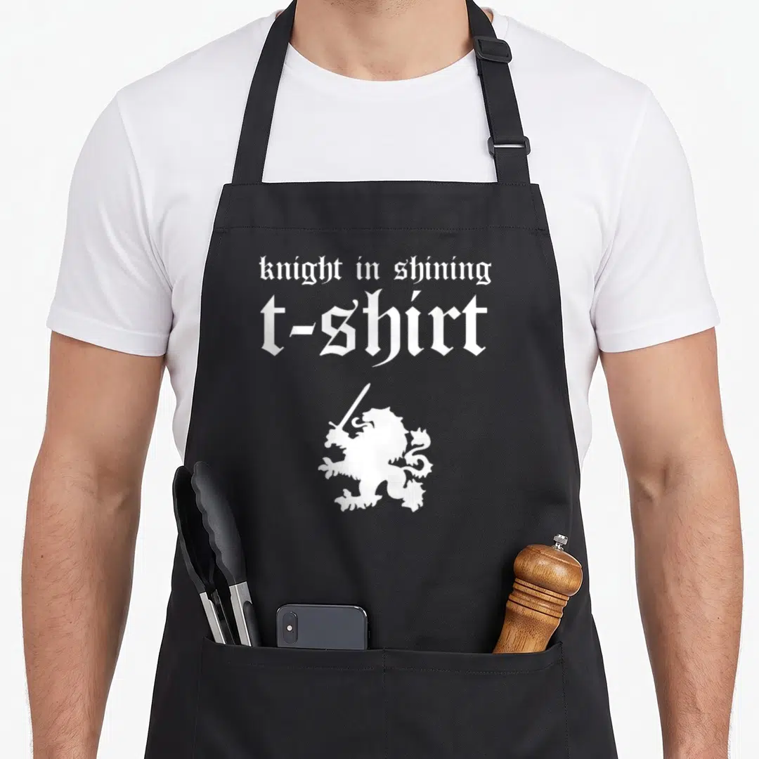 Heraldic renaissance apron - White knight in shining t-shirt text above heraldic lion holding sword — shown on a black cotton canvas apron against a white background