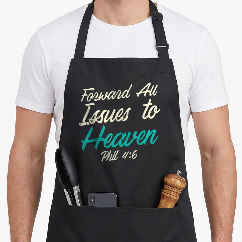 Catholic bible verse apron - Stacked Forward All Issues To Heaven Phil 4:6 text in off-white and teal script — shown on a black cotton canvas apron against a white background
