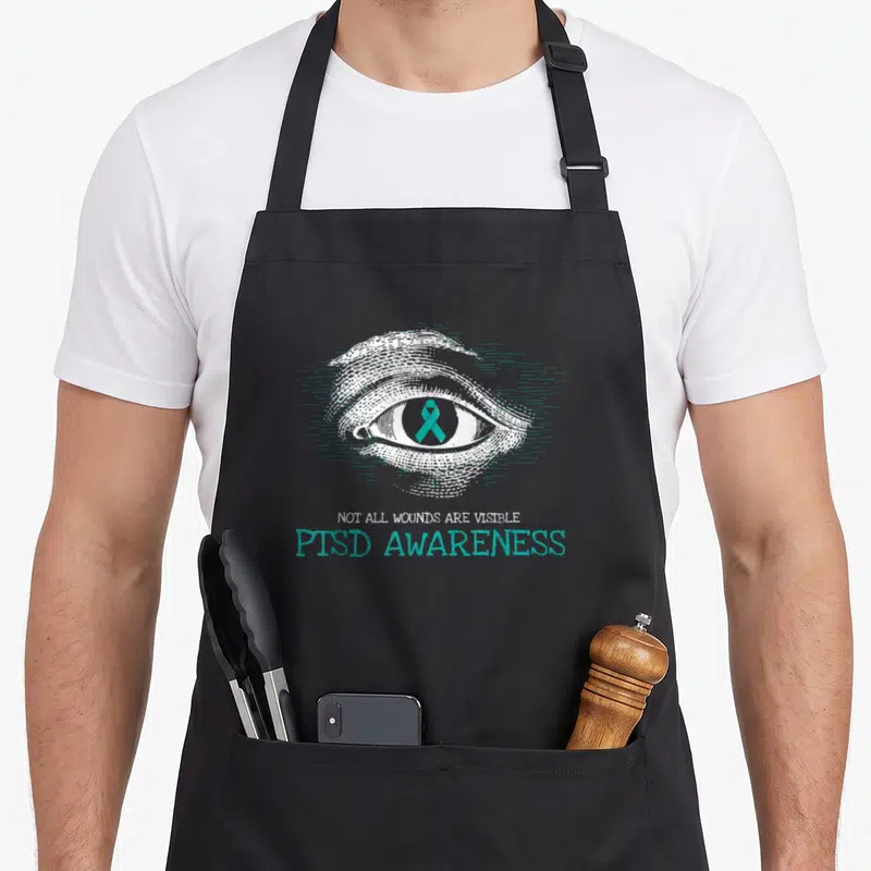 Suicide military apron - Line art eye with teal ribbon and PTSD awareness text — shown on a black cotton canvas apron against a white background