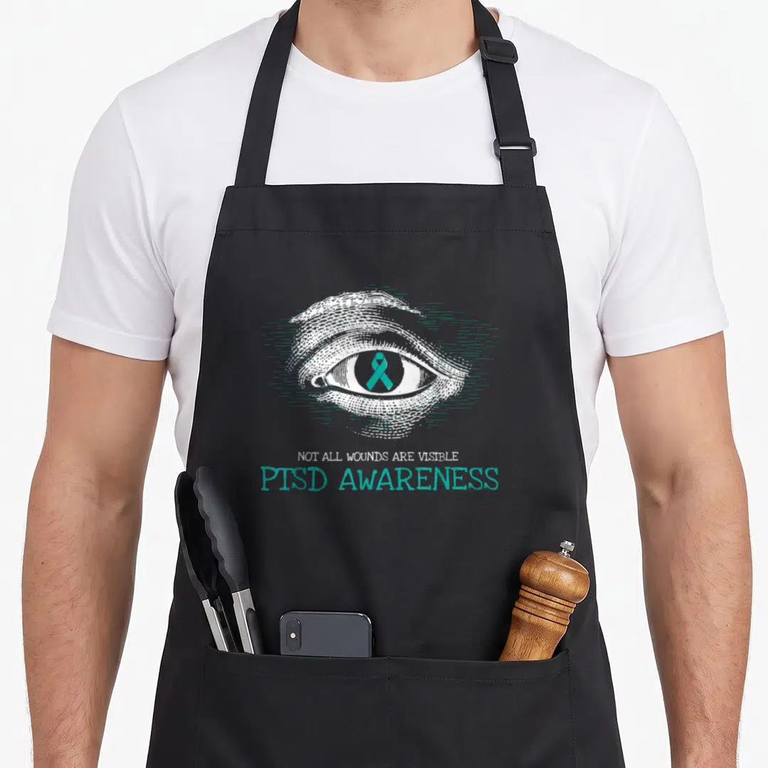 Suicide military apron - Line art eye with teal ribbon and PTSD awareness text — shown on a black cotton canvas apron against a white background