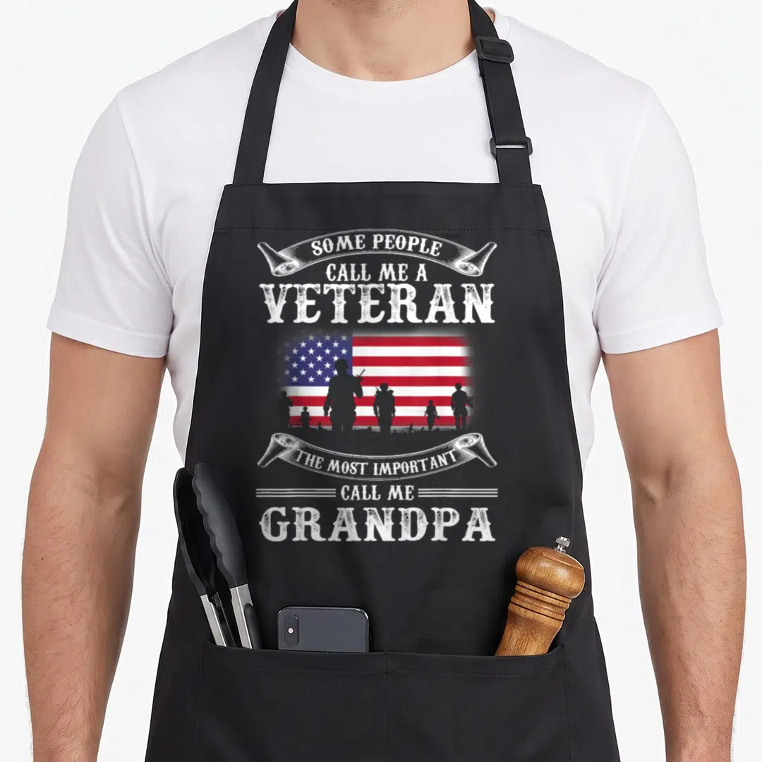 Army father day apron - Veteran Grandpa text with soldier silhouettes and US flag in red white blue — shown on a black cotton canvas apron against a white background