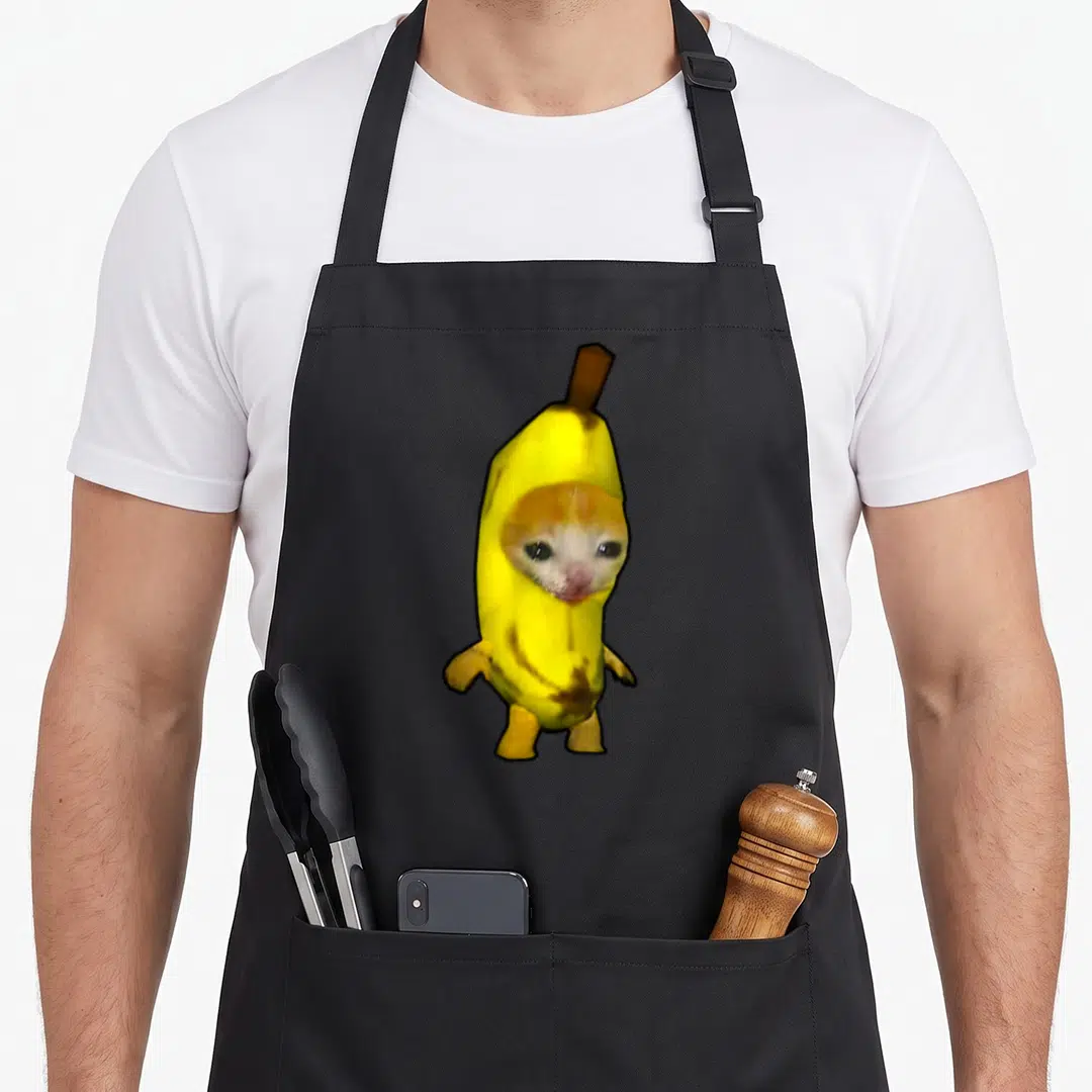Bananacat banana apron - Photo of an orange and white cat wearing a yellow banana costume with a brown stem — shown on a black cotton canvas apron against a white background