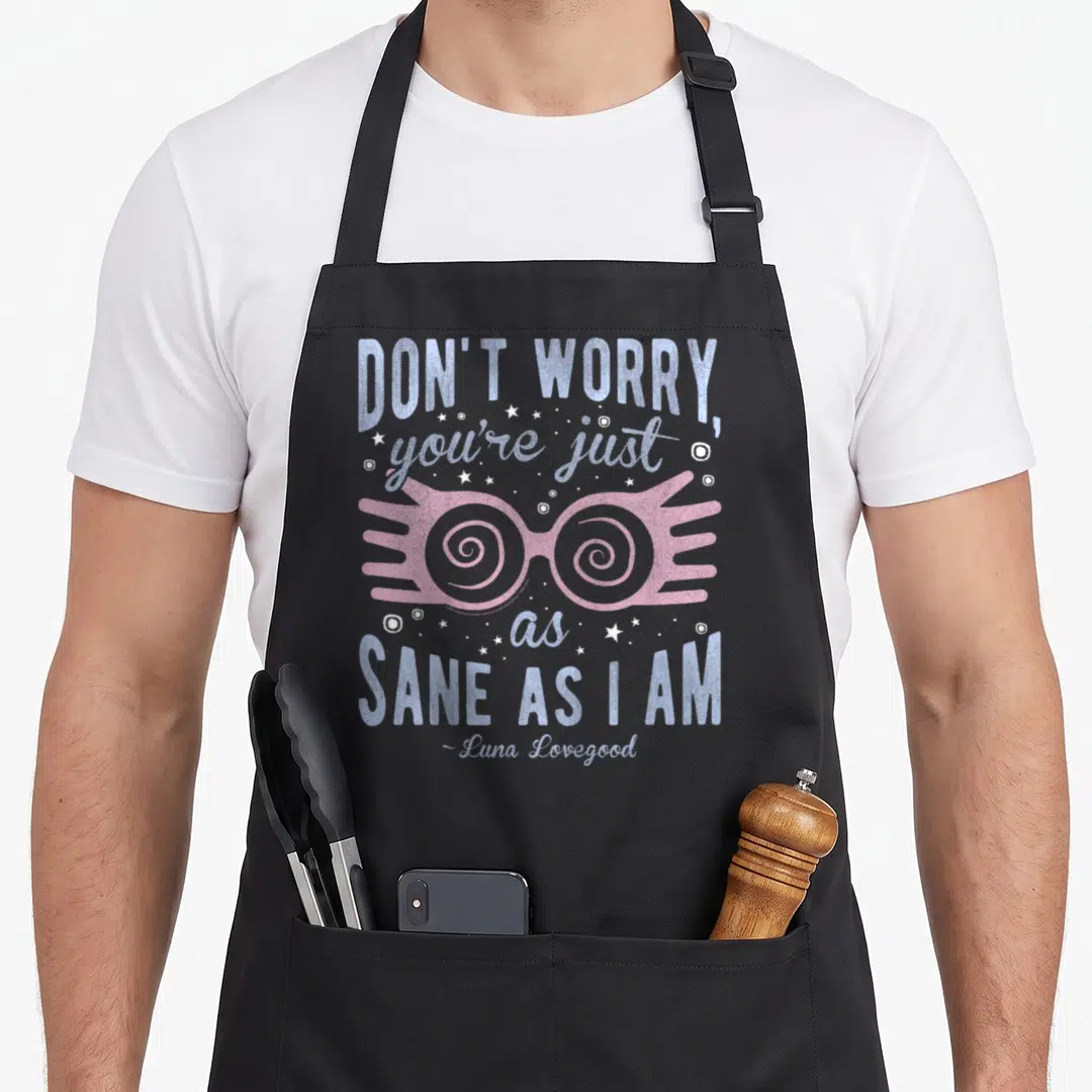 Sane a's aprons - Pink spiral spectacles with blue and white text DON'T WORRY you're just as SANE AS I AM surrounded — shown on a black cotton canvas apron against a white background