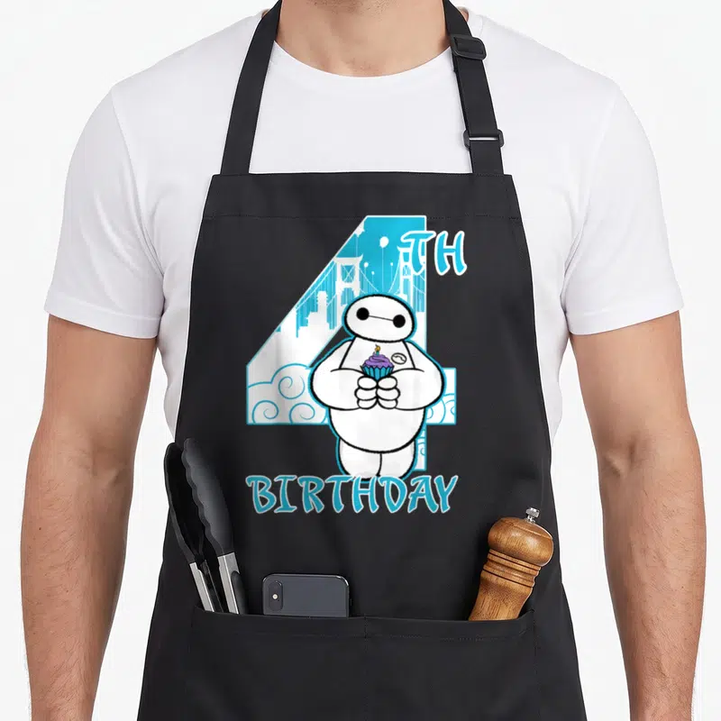 Hero cupcake apron - Baymax holding purple cupcake in front of blue number 4 with 4TH BIRTHDAY text — shown on a black cotton canvas apron against a white background
