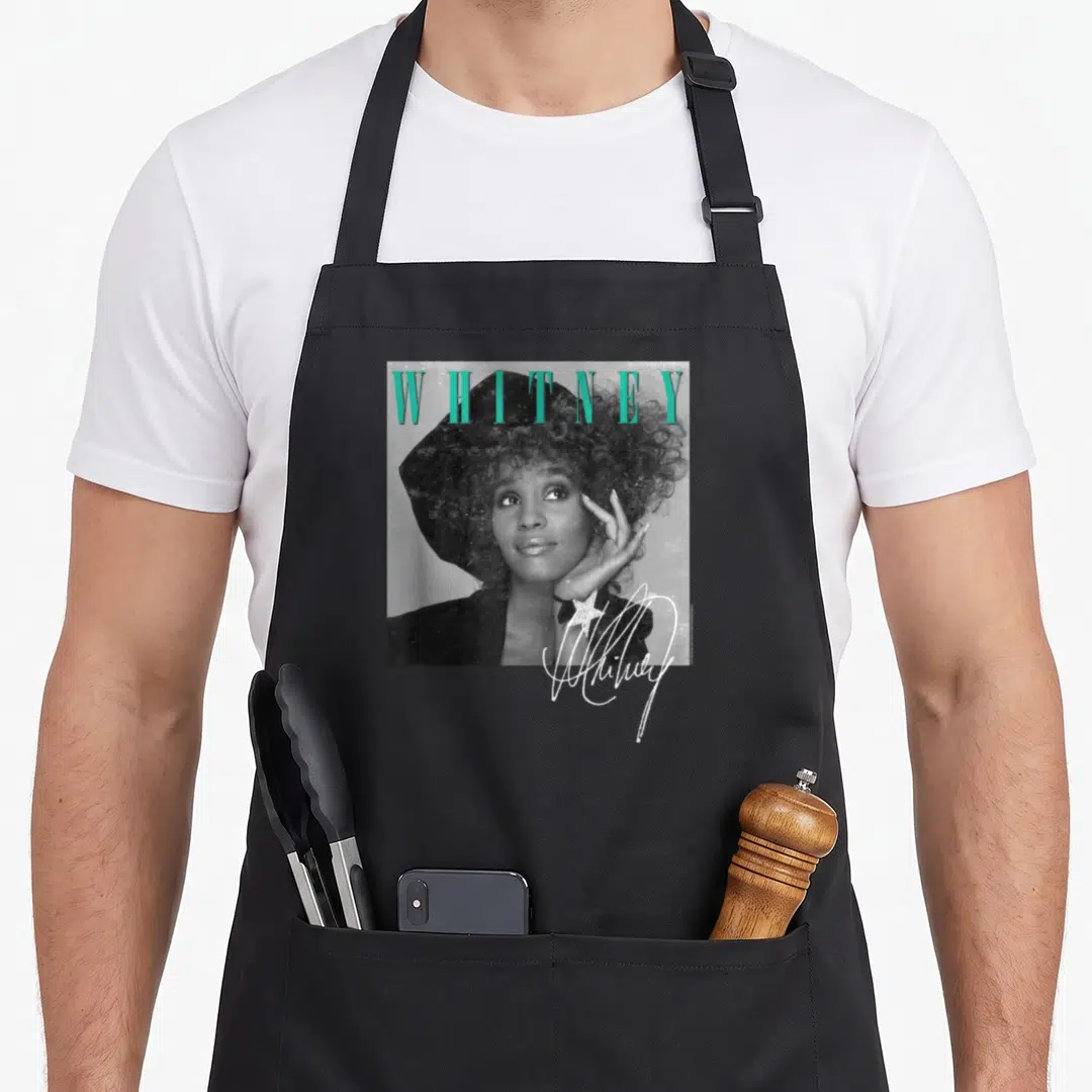 Whitney shooting apron - Grayscale woman in hat with teal WHITNEY text and white signature star — shown on a black cotton canvas apron against a white background