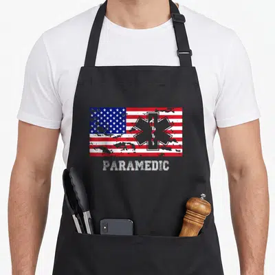 Paramedic emt apron - Distressed USA flag with grey Star of Life and PARAMEDIC text below — shown on a black cotton canvas apron against a white background