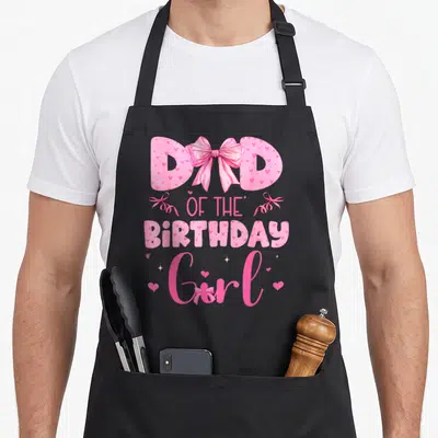 Coquette family aprons - Pink text DAD OF THE BIRTHDAY Girl with bows and hearts — shown on a black cotton canvas apron against a white background