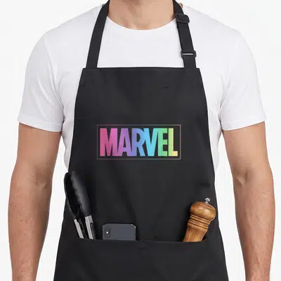 Pastel rainbow apron - MARVEL text in pink blue green yellow gradient inside rectangular border — shown on a black cotton canvas apron against a white background