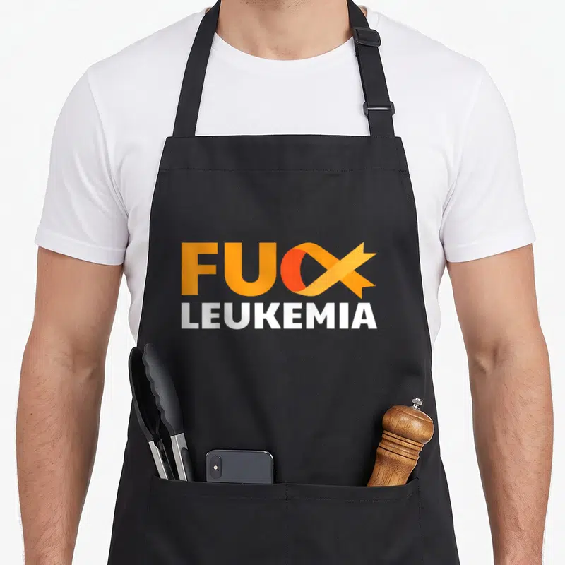 Leukemia awareness ribbon apron - Orange ribbon replaces X in FUX above white LEUKEMIA text — shown on a black cotton canvas apron against a white background