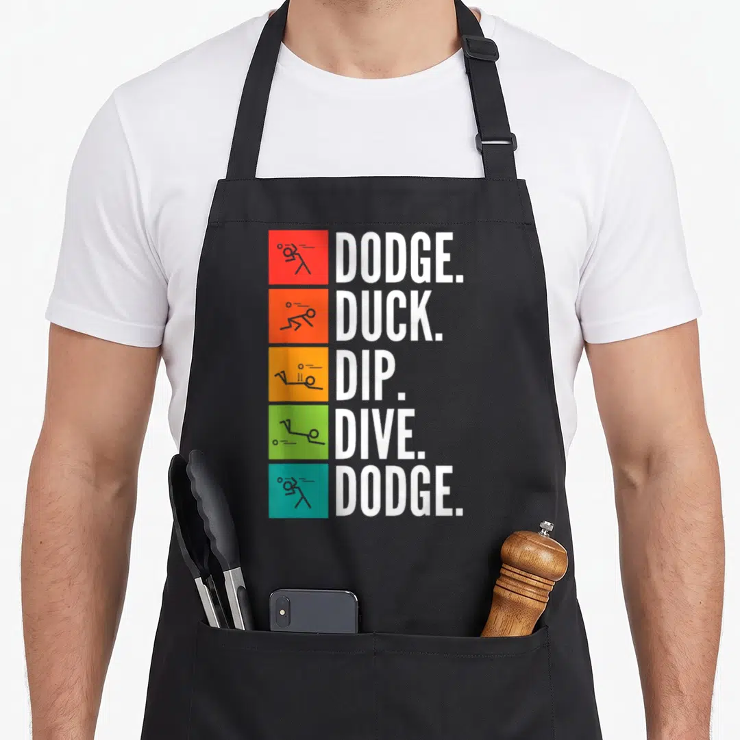 Dip duck apron - Five colored squares with stick figures and dodge duck dip dive dodge text — shown on a black cotton canvas apron against a white background