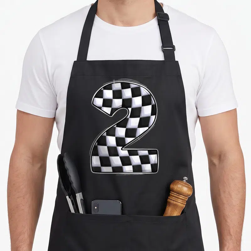 Crew 2nd apron - Cartoon number two filled with black and white checkered racing pattern — shown on a black cotton canvas apron against a white background