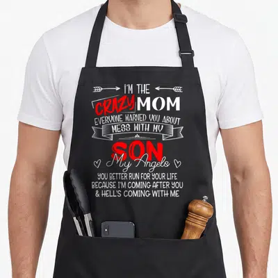Mess mom and son aprons - Vertical white and red text reading Crazy Mom Mess With My Son with arrows ribbon and hearts — shown on a black cotton canvas apron against a white background