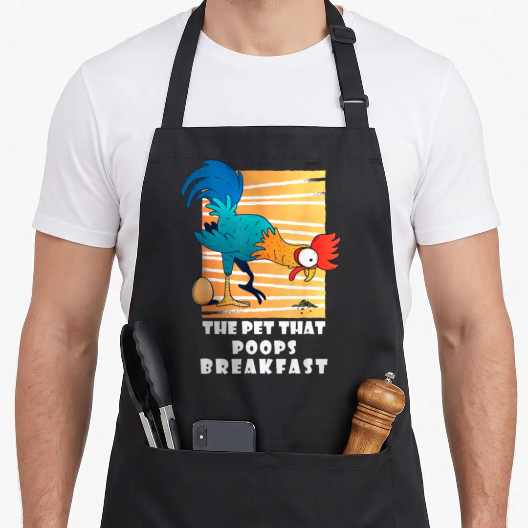 Poop breakfast chicken apron - Cartoon rooster with egg and droppings above white text THE PET THAT, POOPS, BREAKFAST — shown on a black cotton canvas apron against a white background