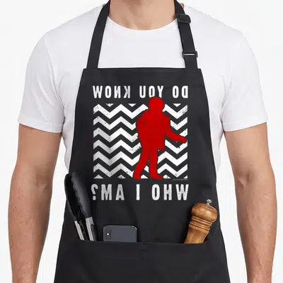 Mystery twin peaks apron - Red person silhouette on white and grey chevron with reversed text DO YOU KNOW WHO I AM — shown on a black cotton canvas apron against a white background