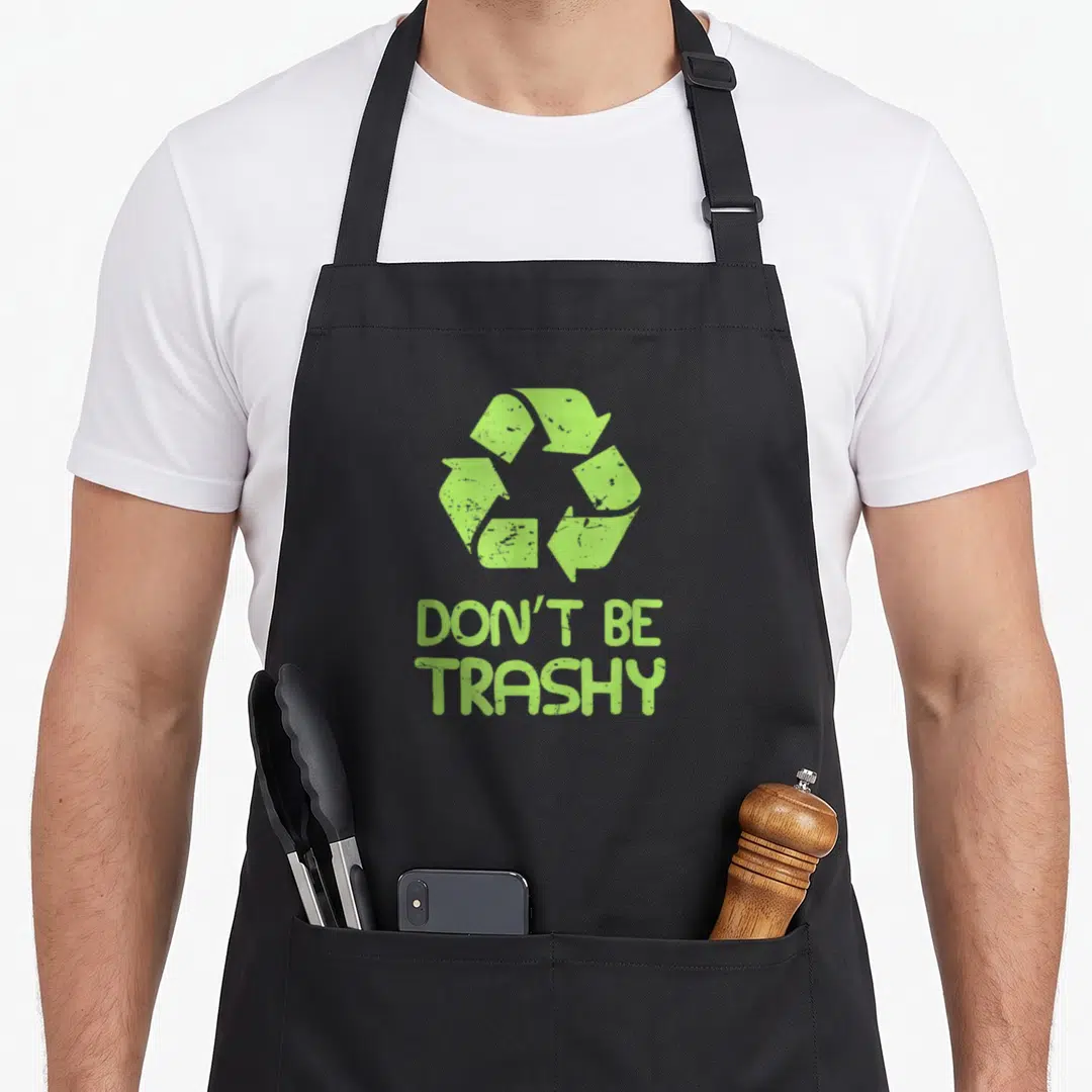Trashy dont give apron - Lime green recycle symbol above distressed DON'T BE TRASHY text — shown on a black cotton canvas apron against a white background