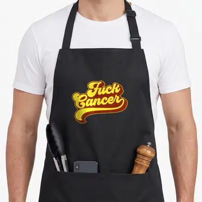 Funny cancer survivor apron - Yellow and brown retro script reading Fuck Cancer with a decorative underline swoosh — shown on a black cotton canvas apron against a white background