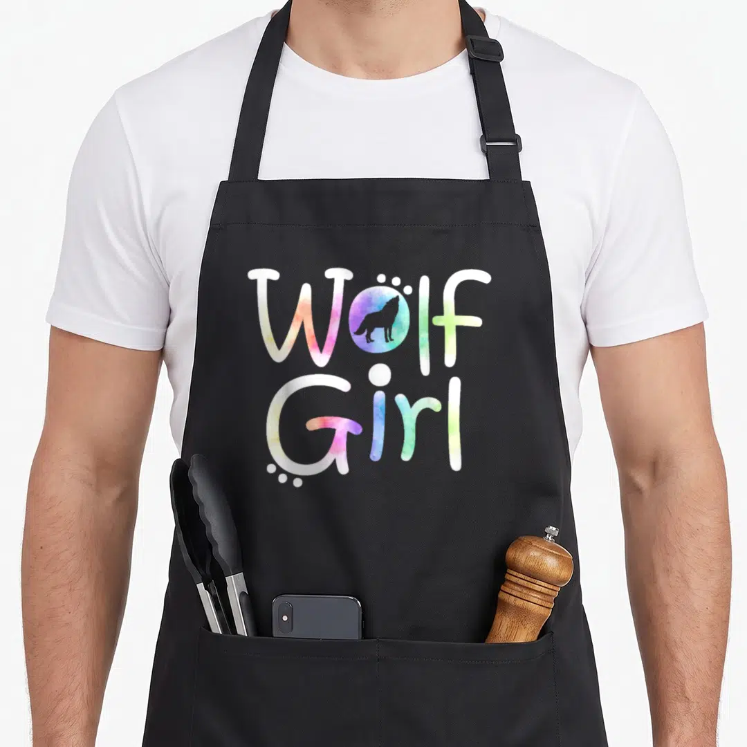 Theme wolves apron - Watercolor Wolf Girl text with rainbow circle wolf silhouette and white dots — shown on a black cotton canvas apron against a white background