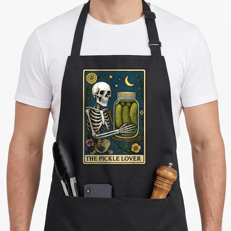 Tarot pickle apron - Skeleton holding pickle jar under moon and stars with text THE PICKLE LOVER — shown on a black cotton canvas apron against a white background