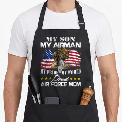 Graduation military apron - My Son My Airman text over boots helmet dog tags and distressed flag with yellow stars — shown on a black cotton canvas apron against a white background