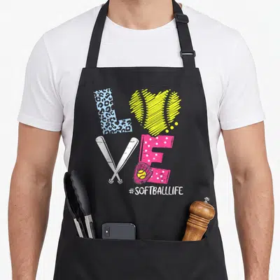 Coach player i love softball apron - LOVE formed by bats glove and leopard print above #SOFTBALLLIFE text — shown on a black cotton canvas apron against a white background