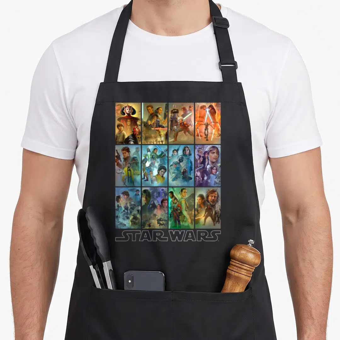 Celebration wars new apron - Grid of 12 Star Wars character posters with white STAR WARS text at bottom — shown on a black cotton canvas apron against a white background