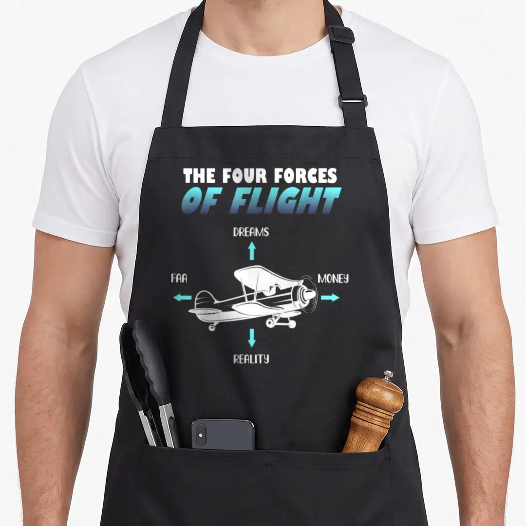 Plane fly aviation apron - Airplane diagram with arrows pointing to Dreams Money FAA Reality text in white and blue — shown on a black cotton canvas apron against a white background