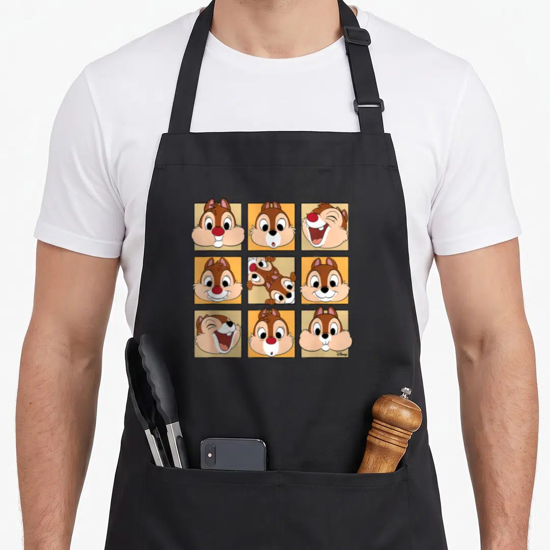 Dale face apron - Nine cartoon chipmunk faces in a grid with brown, orange, and cream coloring — shown on a black cotton canvas apron against a white background
