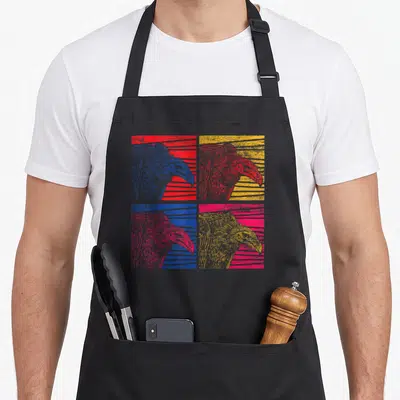 Pop vulture apron - Four vulture heads in red, yellow, blue, and pink arranged in a 2x2 grid with striped backgrounds — shown on a black cotton canvas apron against a white background