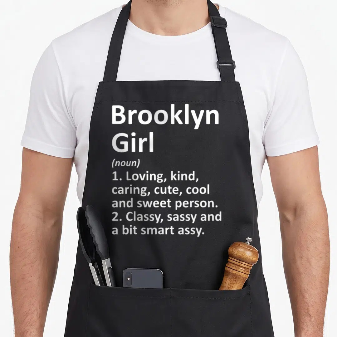 Vintage brooklyn new york apron - White text reading Brooklyn Girl noun definition listing sweet and sassy traits — shown on a black cotton canvas apron against a white background