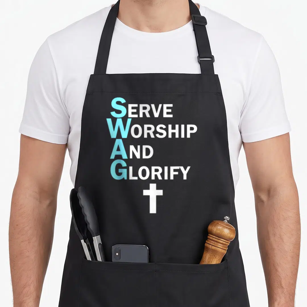 Jesus to serve man apron - Stacked SERVE WORSHIP AND GLORIFY text with blue initials and white cross below — shown on a black cotton canvas apron against a white background