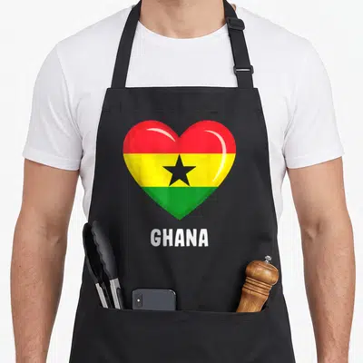 Jersey ghanaian pride apron - Heart-shaped Ghana flag with red yellow green black stripes and white GHANA text below — shown on a black cotton canvas apron against a white background