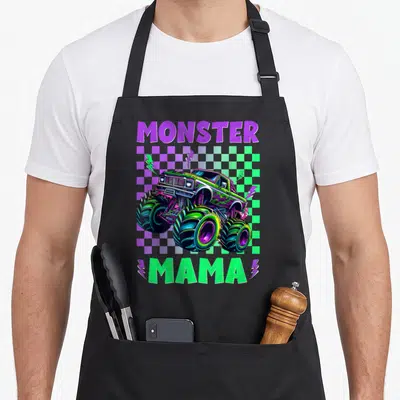 Mama birthday truck apron - Monster Mama text surrounding a truck on purple green checkered background — shown on a black cotton canvas apron against a white background