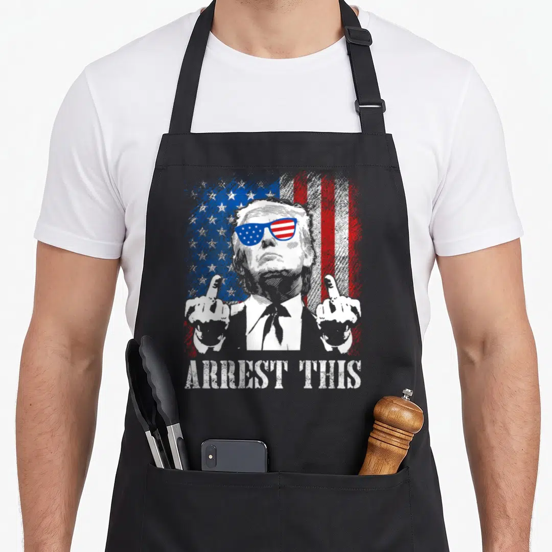 Arrest american flag apron - Distressed Trump portrait with middle finger gesture in front of US flag and ARREST THIS — shown on a black cotton canvas apron against a white background