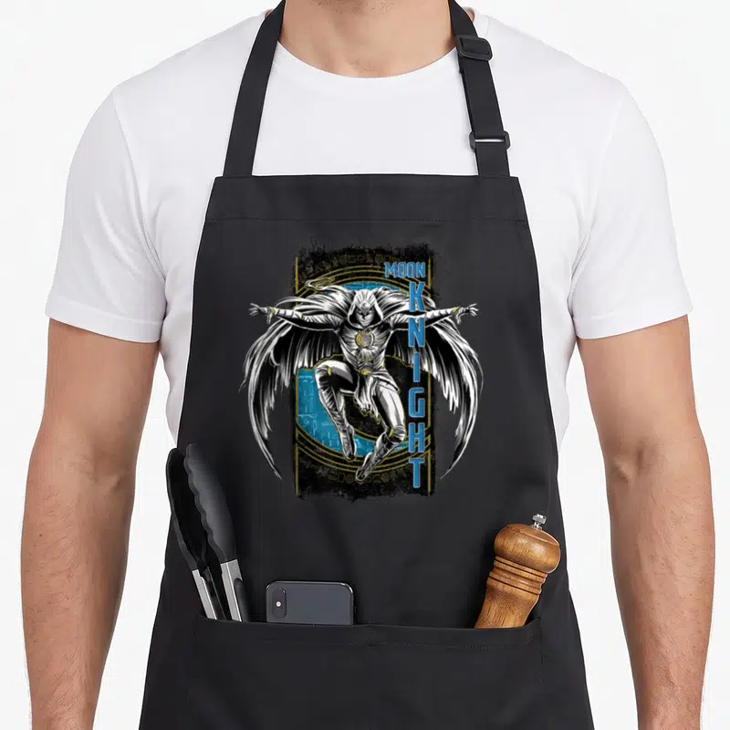 Hieroglyph egyptian apron - Moon Knight character in white costume with blue vertical text and gold hieroglyphic circle — shown on a black cotton canvas apron against a white background