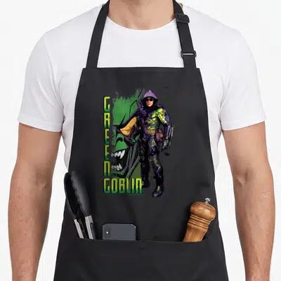 Supervillain goblin apron - Vertical GREEN GOBLIN text beside hooded character with large green face background — shown on a black cotton canvas apron against a white background