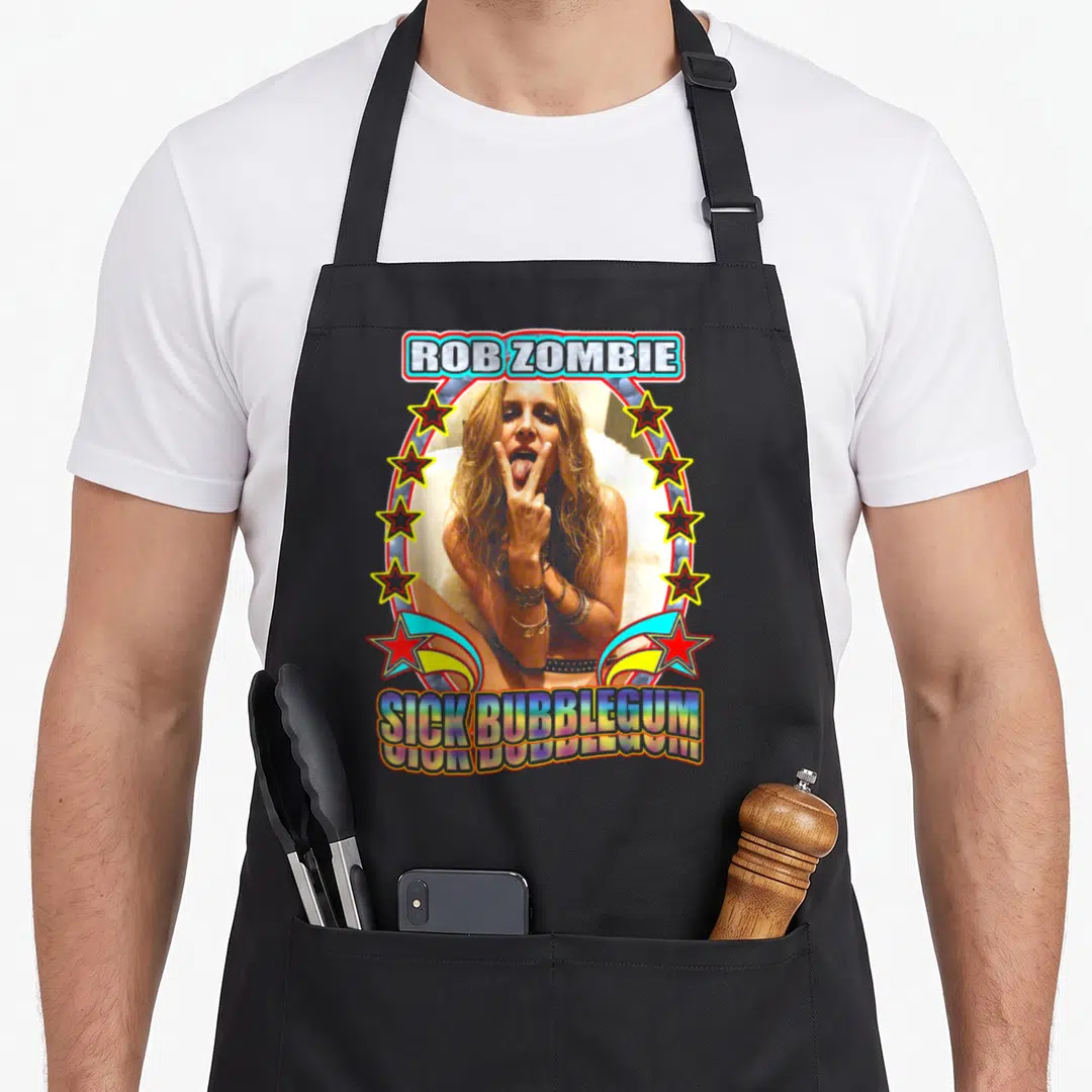 Sick zombie vibes apron - Retro oval graphic with a woman posing, stars, and text ROB ZOMBIE SICK BUBBLEGUM — shown on a black cotton canvas apron against a white background