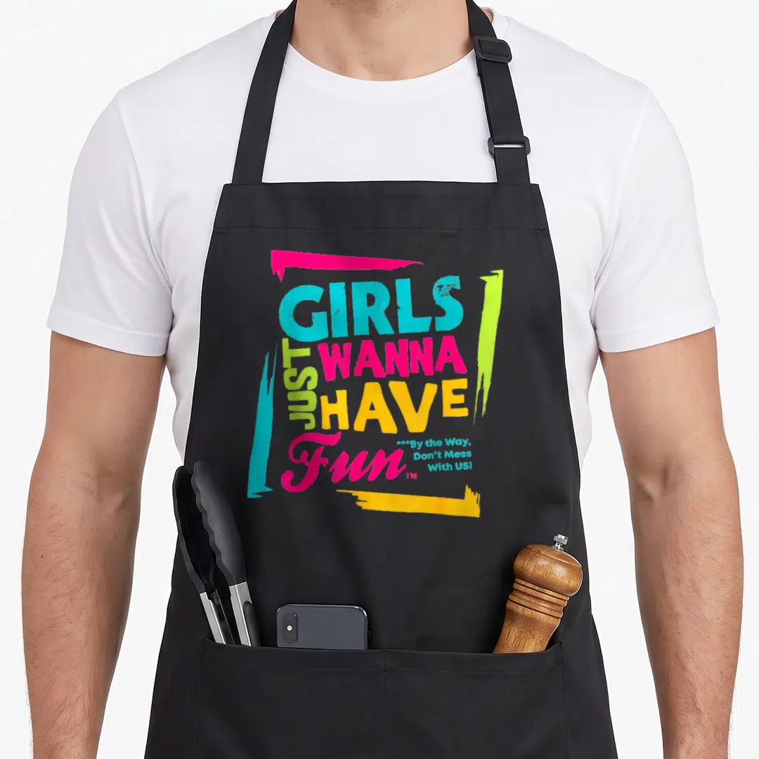 Novelty apron for grilling for men - Stacked text GIRLS JUST WANNA HAVE FUN in cyan magenta lime green and yellow — shown on a black cotton canvas apron against a white background